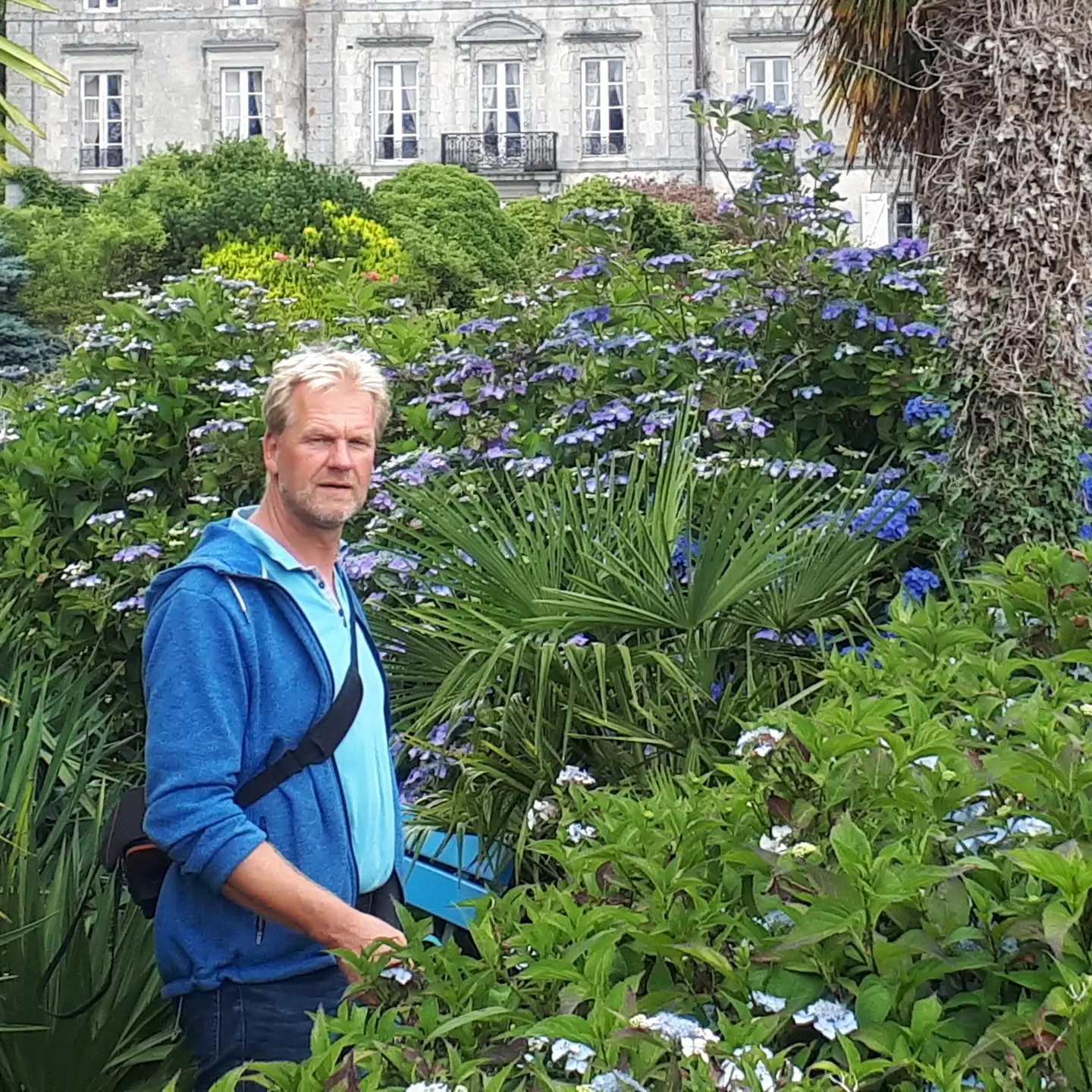 Foto: Der Baumsachverständige Marc Wilde Marc Wilde in einer wundervoll angelegten grünen Gartenanlage mit Sträuchern,
Pflanzen,
Bäumen,
im Hintergrund ein Herrenhaus
